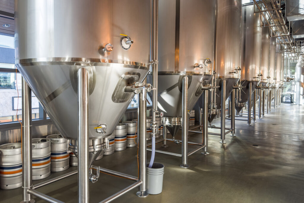 Modern beer factory, row of steel tanks for beer fermentation and maturation.